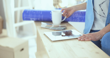 Pretty smiling woman painting interior wall of home with paint roller