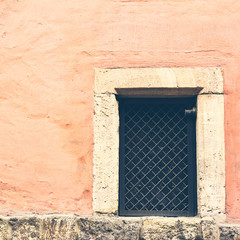 aged pink wall with window with bars
