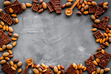 Sweets frame. Broken chocolate slices and nuts on grey stone background top-down copy space