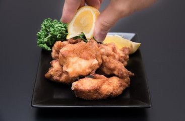 鶏の唐揚げにレモンをかける男性の手元