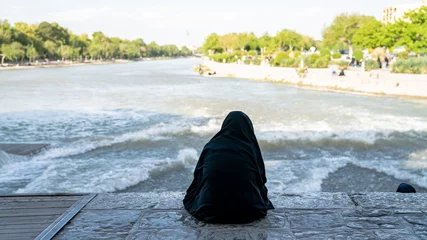 Photo sur Plexiglas Pont Khadjou Femme iranienne assise près de la rivière Zayandeh sur le pont Khaju, Isfahan, Iran