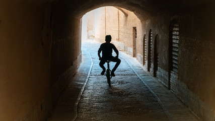 Kid on a bicycle riding in the narrow street of old city Yazd, Iran.