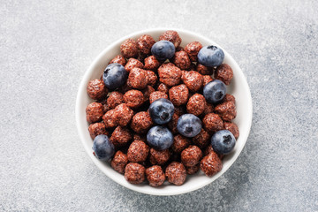 Chocolate flakes made from natural cereals with fresh blueberries, honey and milk. The concept of a healthy wholesome Breakfast. copy space Grey concrete background