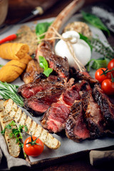 Tomahawk grilled steak cut into pieces with vegetables on a wooden Board, cooking meat barbecue
