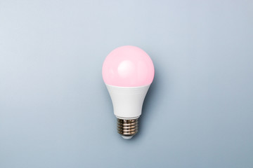 led bulb with pink light against a grey background with copy space. energy efficiency concept