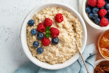 Oatmeal porridge with blueberry, raspberries, jam, top view, close up. Breakfast with berries