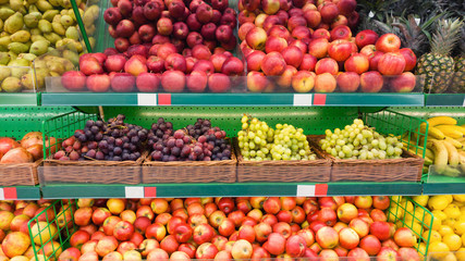 Naklejka na ściany i meble Supermarket shelves with fruits. Apples, grapes and other sweet fruits selling on showcase