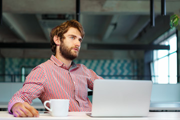 Puzzled thoughtful businessman sitting at his working table in an office. Business concept