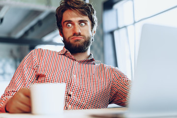 Puzzled thoughtful businessman sitting at his working table in an office. Business concept