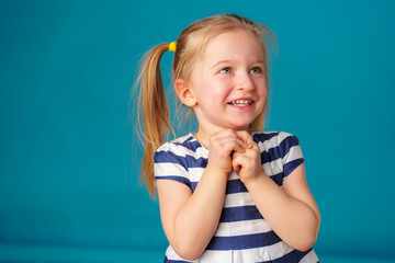 Funny little toddler girl smiling  against blue background