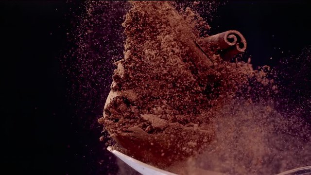A Full Spoon Of exotic Christmas spice cinnamon anise and nutmeg falling down  on black background closeup in super slow motion
