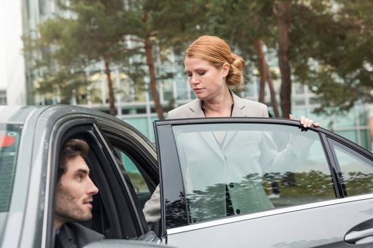 Businessfrau steigt bei Chauffeur ins Auto ein