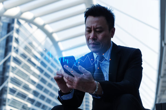 investor or business man sitting and using mobile smart phone with visual graphic graph chart of stock market investment trading for Forex trading, stock market, investment, digital technology concept