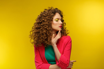 Fototapeta premium Fashion studio portrait of young beautiful women with curly hair.Nice girl with wavy hairstyle and bright make up isolated over yellow background.Beauty and hair care concept,yellow lifestyle.