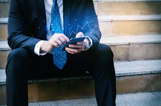 investor or business man sitting and using mobile smart phone with visual graphic graph chart of stock market investment trading for Forex trading, stock market, investment, digital technology concept