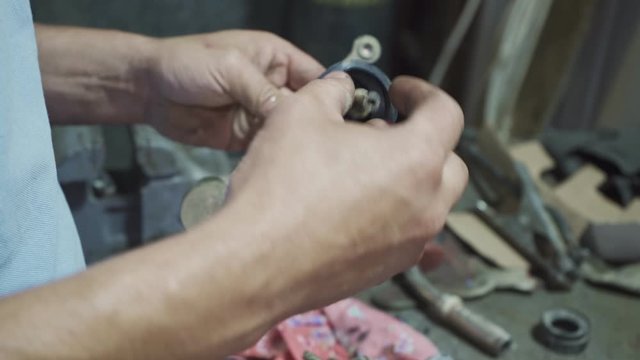 A mechanic repairing a part from a car chassis