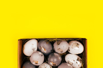 Silver painted decorative eggs in wooden box on bright yellow background. Easter concept. Place for text.