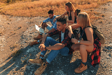 Group of four friends hiking through countryside together at sunset.