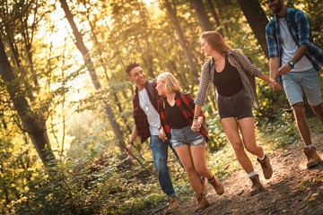 Group of four friends having fun hiking through forest together.