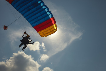 Detail of a canopy of a parachute and silhouettes of an instructor and a passenger during a tandem...