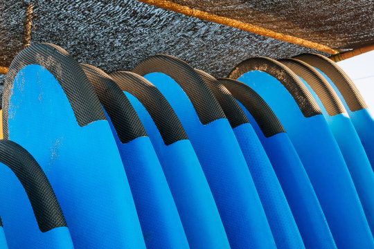 Close up stack of blue color soft surfboards in a stack by ocean.Bali.Indonesia. Surf boards on sandy beach for rent. Surf lessons on Weligama beach, Sri Lanka.