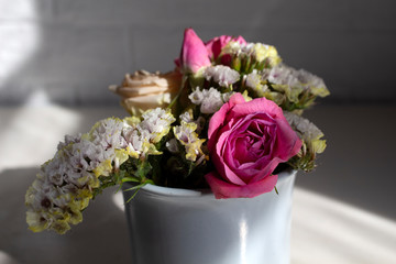 Pink roses, cream roses and white limonium in a vase.