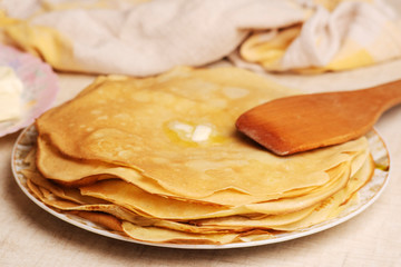 Pancakes on the white plate. Many pancakes are stacked. Thin pancakes with crispy crust. Maslenitsa. Pancakes for breakfast and carnival. Food background.