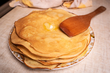 Pancakes on the white plate. Many pancakes are stacked. Thin pancakes with crispy crust. Maslenitsa. Pancakes for breakfast and carnival. Food background.