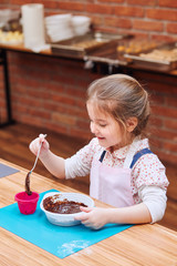 Little chef stirring hot melted chocolate with cocoa. Kid taking part in baking workshop. Baking classes for children,  aspiring little chefs. Learning to cook. Combining and stirring ingredients