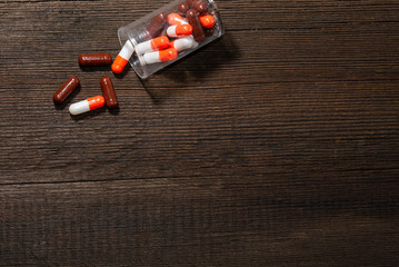 Red-white and brown capsule pills on a wooden background. Pharmacy.