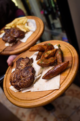 Tasty fried steaks and potatoes in a rustic style on wooden trays.