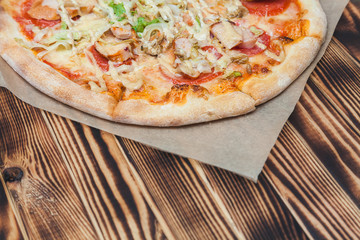 Caesar pizza with lettuce, chicken, soyce, tomatoes, cheese on a wooden table