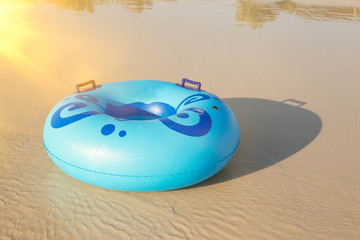 Inflatable ring player with soft wave of blue ocean on sandy beach. Background of travel in summer season