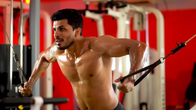 Muscular bodybuilder at cable crossovers fitness men pumping up muscles. Workout fitness exercises and bodybuilding concept background