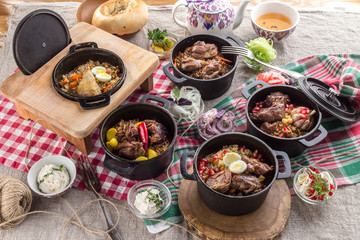 Assorted Uzbek food pilaf rice with meat served in iron pots on fabric background