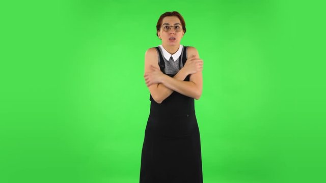 Funny girl in round glasses froze and trying to keep warm. Green screen