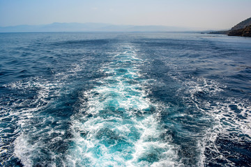 the trace of a cruise ship on blue sea water, foaming bubbles on the surface of sea water