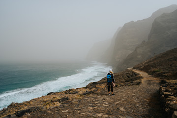 Fototapeta premium Santo Antao, Cape Verde - Female hiker on trail hike Cruzinha da Garca to Ponta do Sol. Moody Atlantic ocean coastline