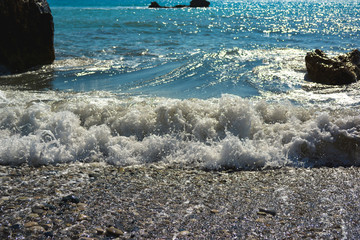 sea foam of seawater rolls on the shore with rocks