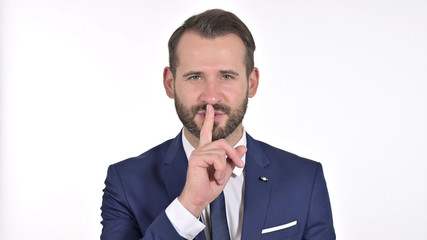 Portrait of Young Businessman Putting Finger on Lips, White Background
