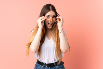 Young caucasian woman isolated on pink background with glasses and smiling