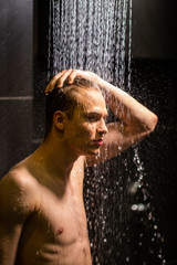 Fototapeta na wymiar handsome guy washes in the shower