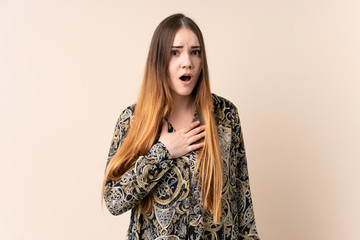 Young caucasian woman isolated on beige background surprised and shocked while looking right