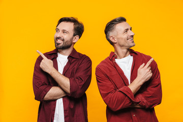 Image of handsome men smiling and pointing fingers upwards at copyspace