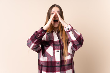 Young caucasian woman isolated on beige background shouting and announcing something