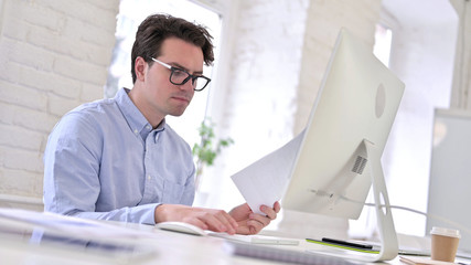 Working Young Man Reading Documents in Office