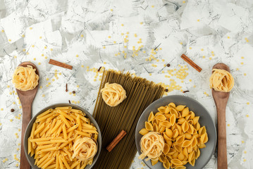 dry paste on gray ceramic dishes and wooden spoons with various seasonings on a textured gray-white...