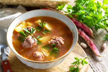 The concept of healthy and diet food, vegetarian dish. Delicious Vegetable soup with bean balls on a rustic table.