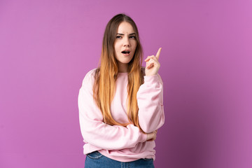 Young caucasian woman isolated on purple background thinking an idea pointing the finger up