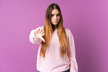 Obraz premium Young caucasian woman isolated on purple background showing thumb down with negative expression